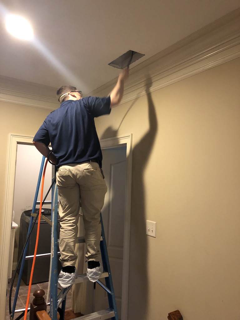 man on a ladder doing a HVAC Duct Cleaning in Cumming